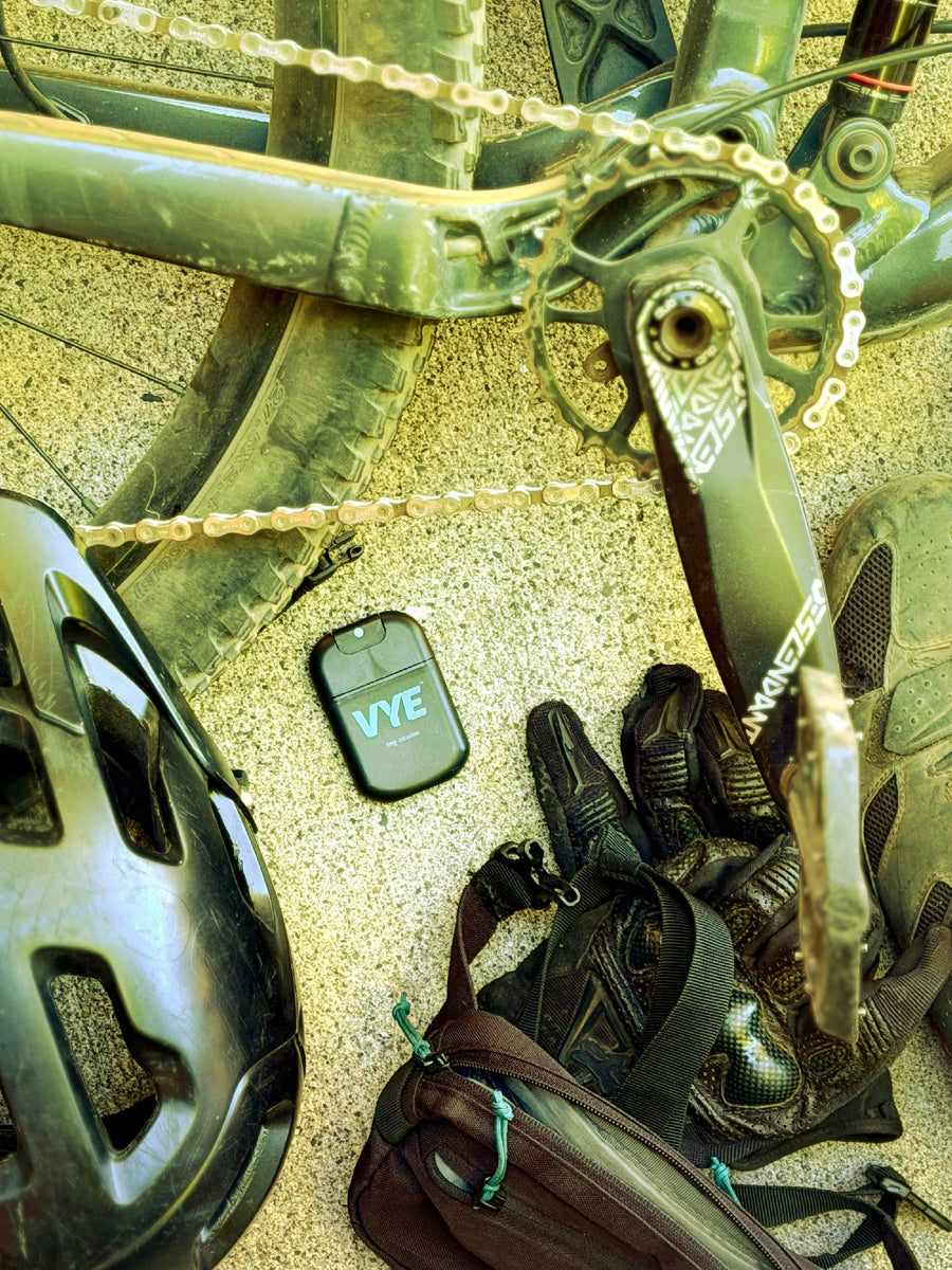 A VYE mist device rests beside a bicycle wheel and chain.