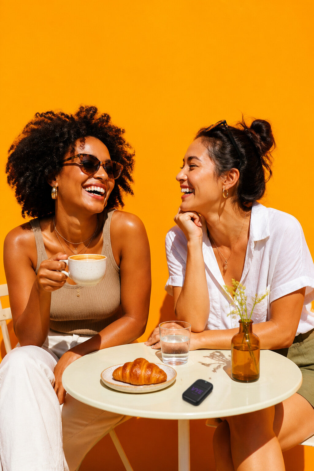 Friends seated at a cafe table with drinks, a VYE sprayer on the table.
